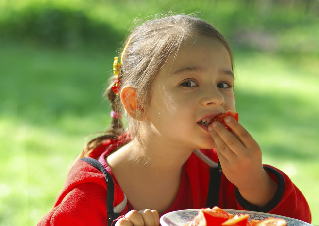 Girl bites tomato